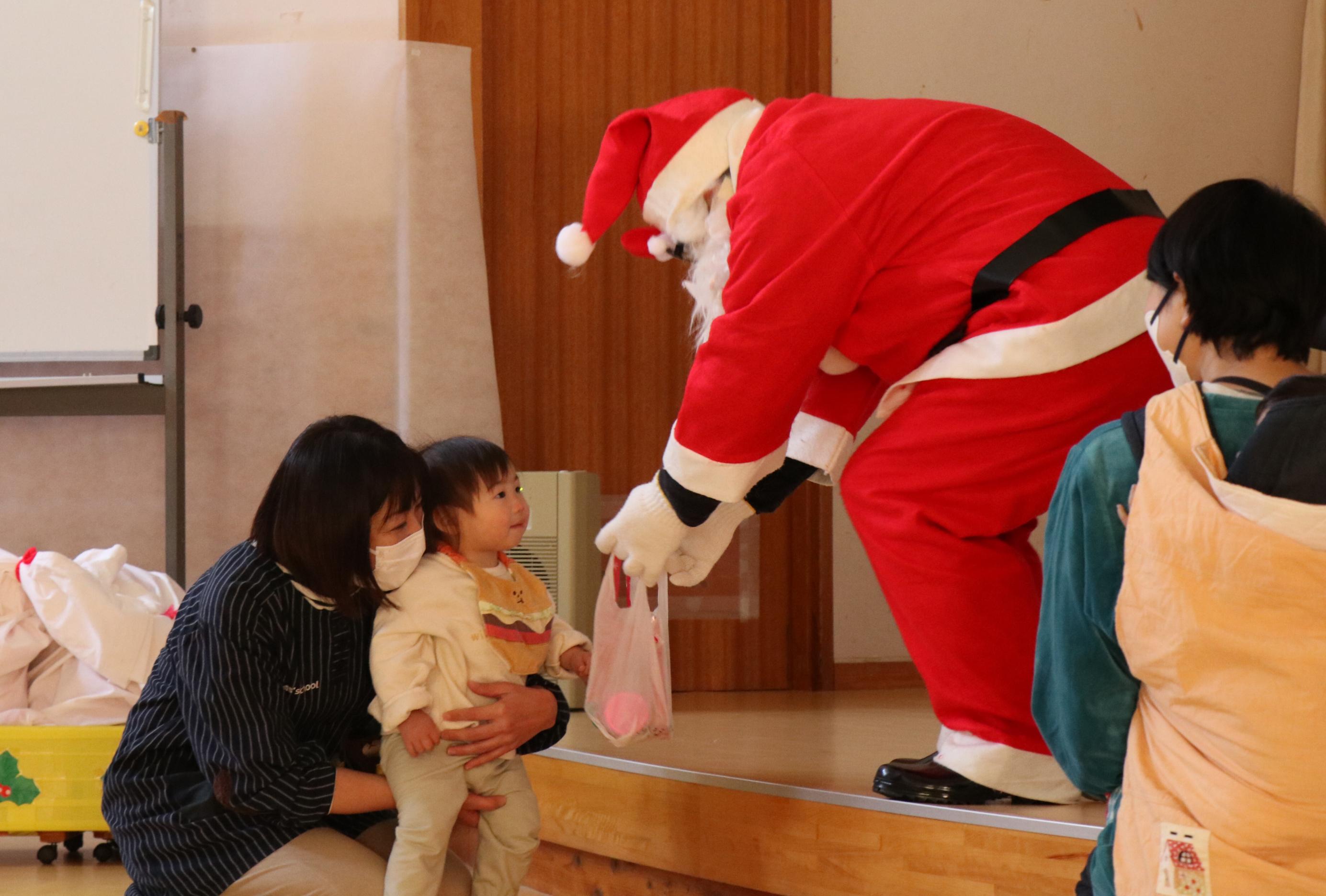 伊王野保育園クリスマス会で園児がサンタクロースからプレゼントをもらう様子