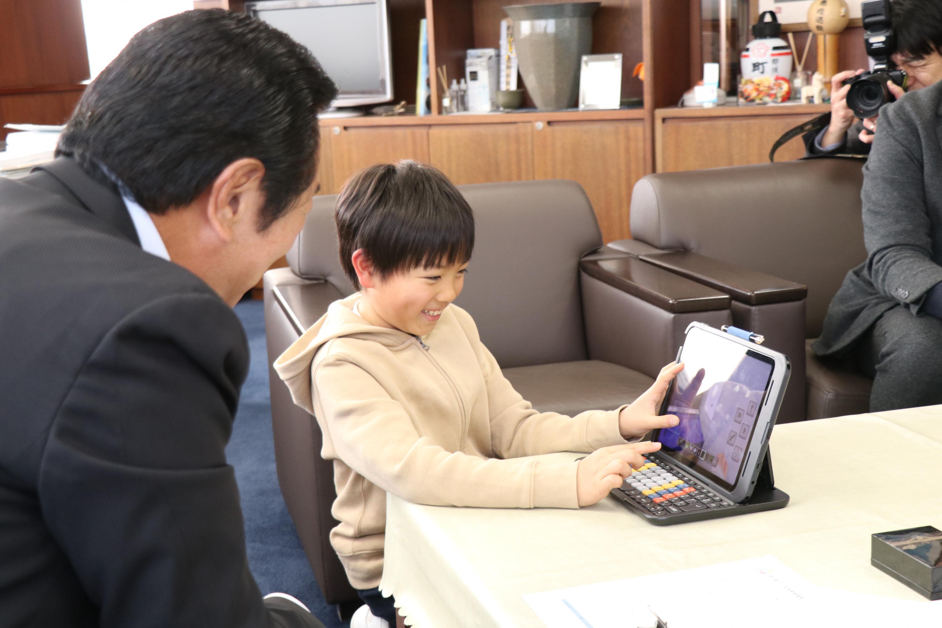 砂川さんが平山町長に作成した作品を説明する様子